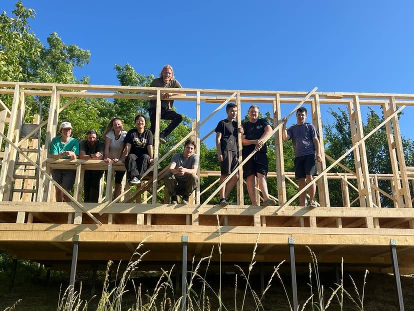 Team on the frame of a Tiny House eco-cabin made of wood and straw